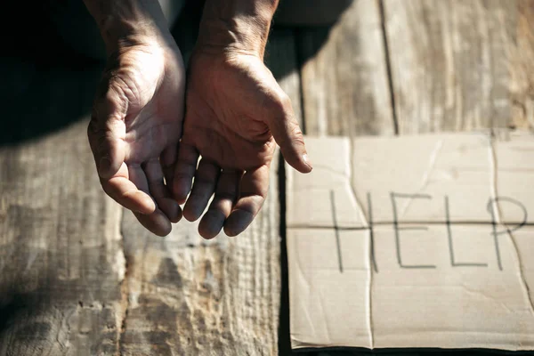 Mãos de mendigo masculino buscando dinheiro no chão de madeira no caminho público — Fotografia de Stock