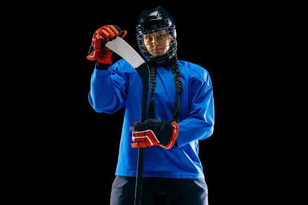 Ung kvinnlig hockeyspelare med klubban isolerad på svart bakgrund — Stockfoto