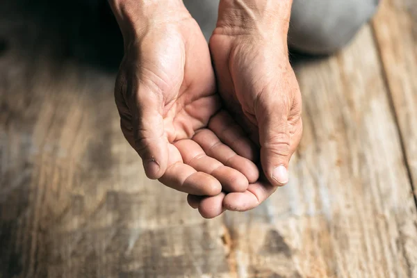 Mãos de mendigo masculino buscando dinheiro no chão de madeira no caminho público — Fotografia de Stock