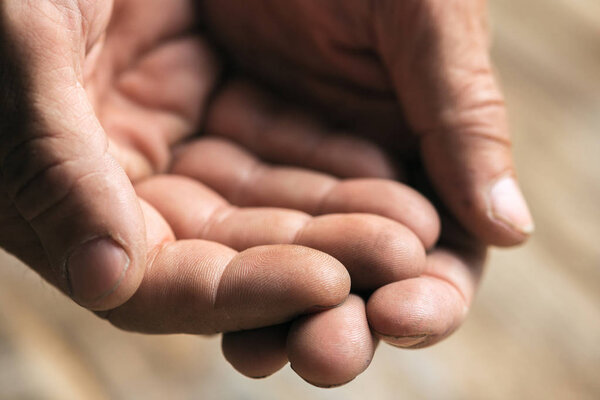 Male beggar hands seeking money on the wooden floor at public path way