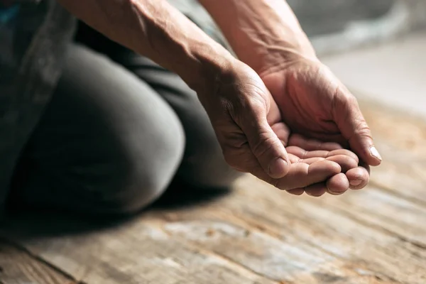 Male beggar hands seeking money on the wooden floor at public path way — Stock Photo, Image