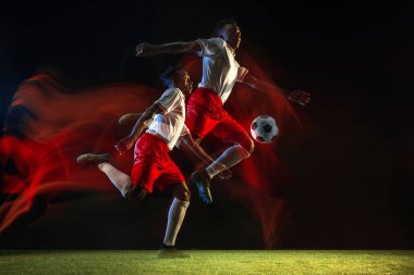 Erkek futbolcu karışık ışıkta koyu arka planda topa tekme