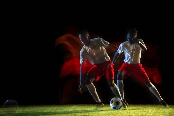Erkek futbolcu karışık ışıkta koyu arka planda topa tekme — Stok fotoğraf