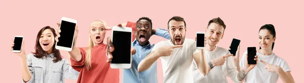 Portrait of people showing screen of mobile phone isolated over coral background — Stock Photo, Image