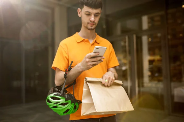 Jovem como um mensageiro entregando pacote usando gadgets — Fotografia de Stock