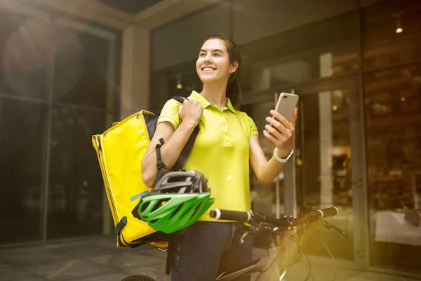 Mujer joven como mensajera entregando comida usando gadgets — Foto de Stock