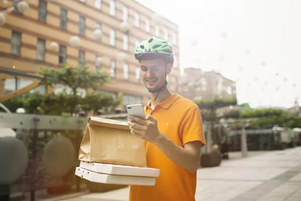 Joven como mensajero entregando pizza usando gadgets —  Fotos de Stock