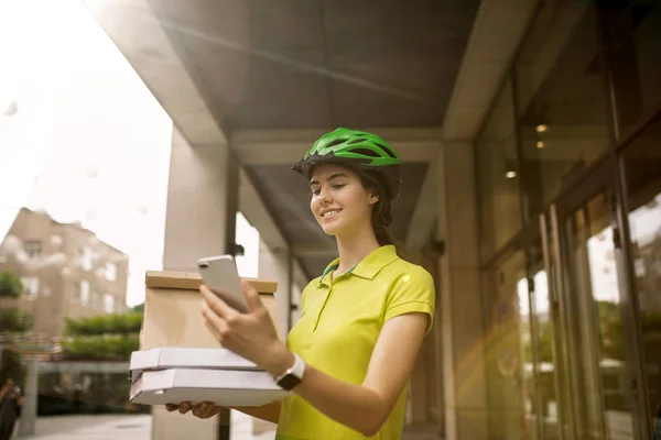 Jonge vrouw als koerier leveren pizza met behulp van gadgets — Stockfoto