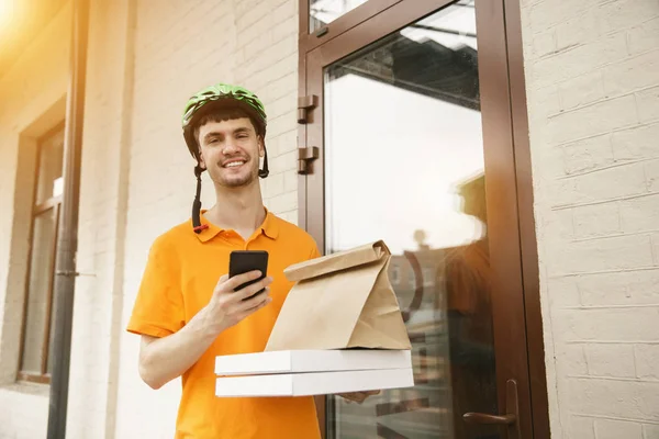 Jongeman als koerier leveren pizza met behulp van gadgets — Stockfoto