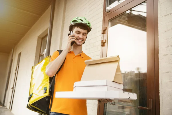 Mladý muž jako kurýr doručující pizzu pomocí gadgets — Stock fotografie