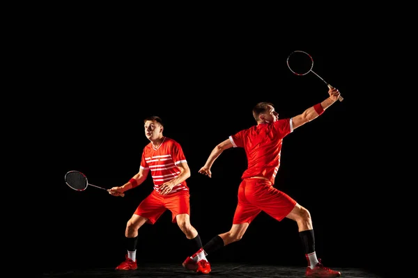 Ung man spelar badminton isolerad på svart studio bakgrund — Stockfoto