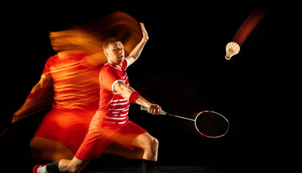 Ung man spelar badminton isolerad på svart studio bakgrund — Stockfoto