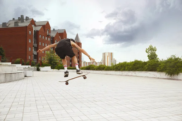 Skateboarder robi sztuczkę na ulicy miejskich w zachmurzenie dzień — Zdjęcie stockowe