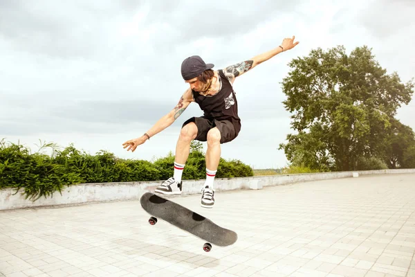 Skateboarder doing a trick at the citys street in cloudly day — Stock Photo, Image