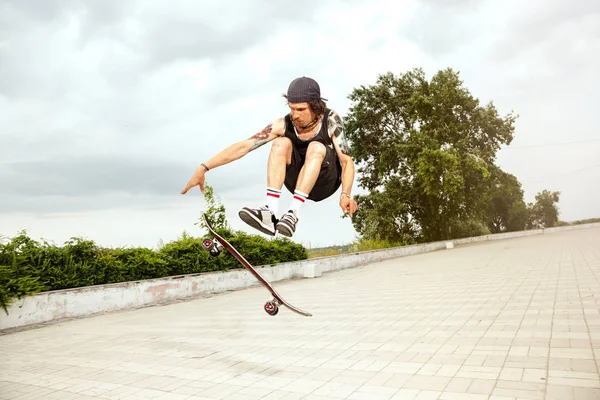 Skateboarder robi sztuczkę na ulicy miejskich w zachmurzenie dzień — Zdjęcie stockowe