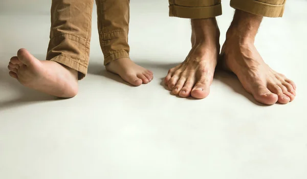 白いスタジオの背景、お父さんと息子の家族の足 — ストック写真