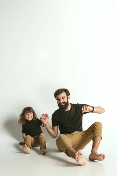 Pai brincando com o filho jovem contra o fundo do estúdio branco — Fotografia de Stock