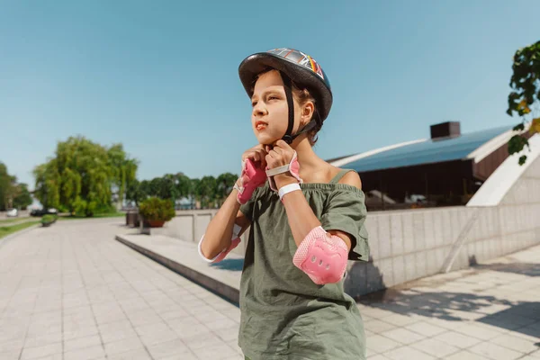 Adolescente en un casco aprende a montar en patines al aire libre —  Fotos de Stock