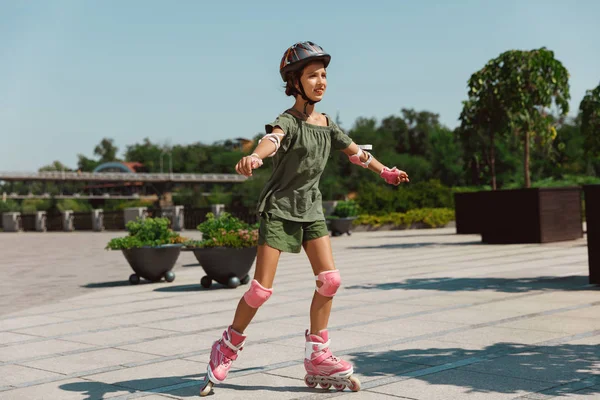 Tiener meisje in een helm leert om te rijden op rolschaatsen buitenshuis — Stockfoto