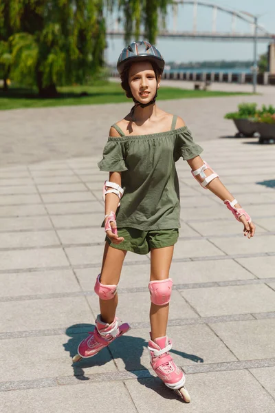 Adolescente en un casco aprende a montar en patines al aire libre —  Fotos de Stock