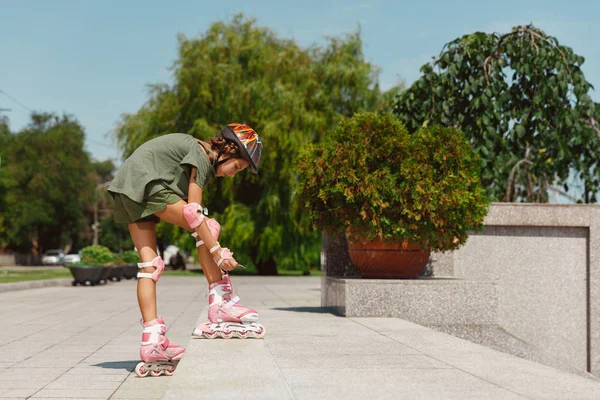 Tiener meisje in een helm leert om te rijden op rolschaatsen buitenshuis — Stockfoto