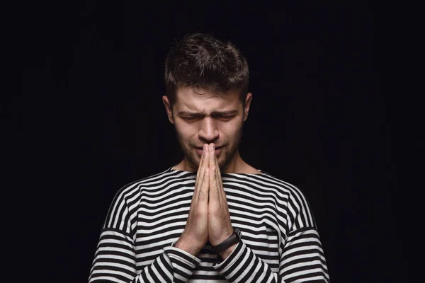 Close up portrait of young man isolated on black studio background