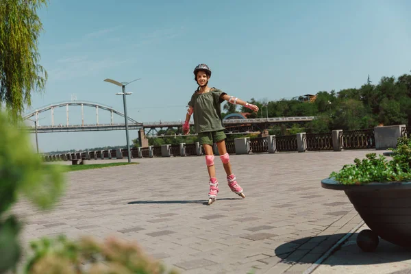 Adolescente en un casco aprende a montar en patines al aire libre — Foto de Stock
