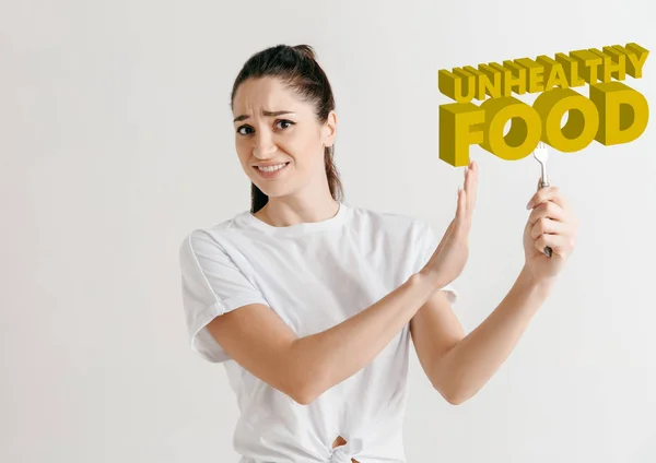 Concepto de comida. Modelo sosteniendo un plato con letras de alimentos poco saludables — Foto de Stock