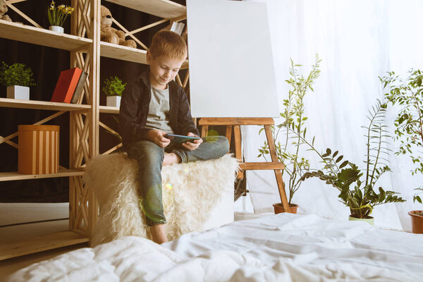 Little boy using different gadgets at home