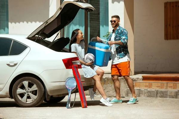 Молода пара готується до відпустки на машині в сонячний день — стокове фото
