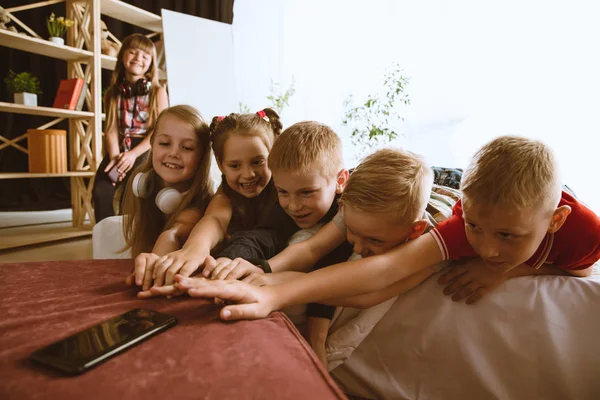 Kleine Jungen und Mädchen mit verschiedenen Geräten zu Hause — Stockfoto