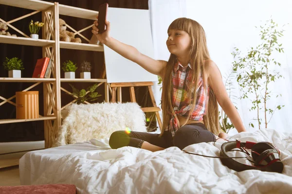 Маленька дівчинка використовує різні гаджети вдома — стокове фото