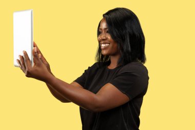 Sarı stüdyo arka planında izole edilmiş genç Afrikalı kadın, yüz ifadesi