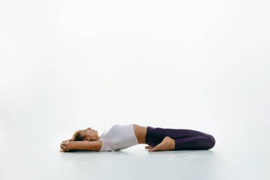 Beyaz arka planda yalnız başına yoga yapan genç bir kadın.