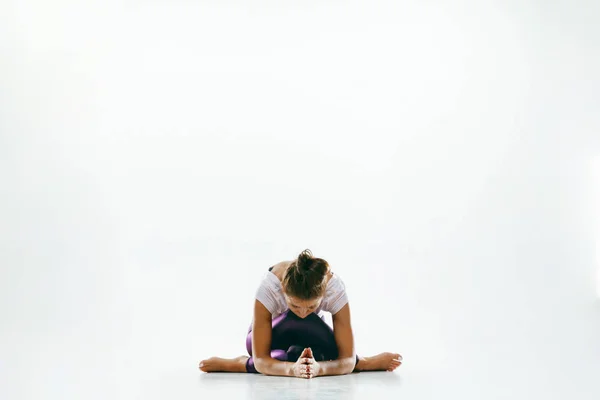 Beyaz arka planda yalnız başına yoga yapan genç bir kadın. — Stok fotoğraf