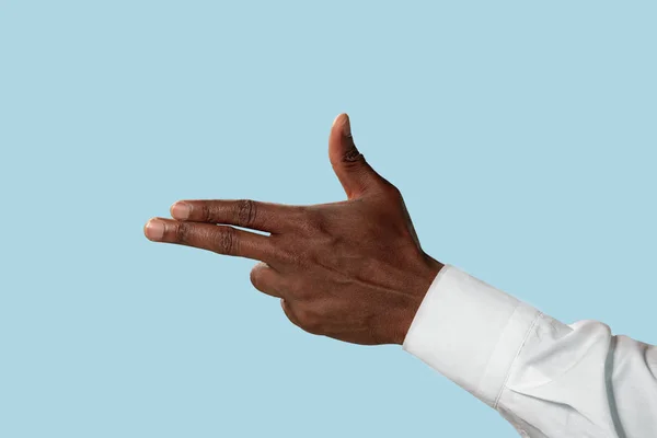 Male hand demonstrating a gesture of gun isolated on blue background — Stock Photo, Image