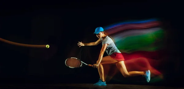 混合光の中で黒い背景でテニスをしている白人女性 — ストック写真