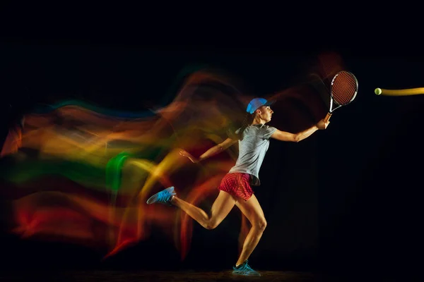 Una mujer caucásica jugando tenis sobre fondo negro en luz mixta —  Fotos de Stock