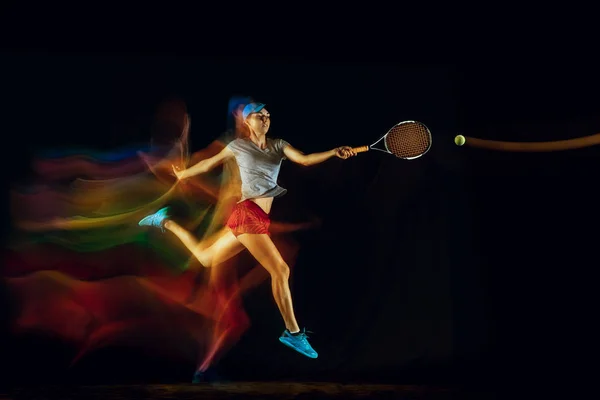 One caucasian woman playing tennis on black background in mixed light — Stock Photo, Image