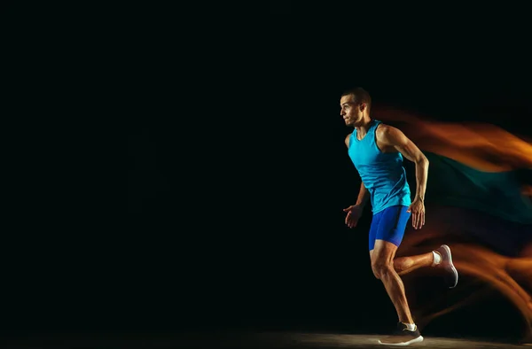 Profesjonalny trening męski biegacz izolowany na czarnym tle studio w świetle mieszanym — Zdjęcie stockowe