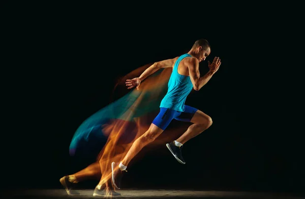 Profesjonalny trening męski biegacz izolowany na czarnym tle studio w świetle mieszanym — Zdjęcie stockowe
