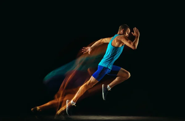 Професійне тренування чоловіків бігунів ізольовано на чорному студійному фоні у змішаному світлі — стокове фото