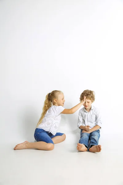Menino e menina jogando juntos no fundo do estúdio branco — Fotografia de Stock