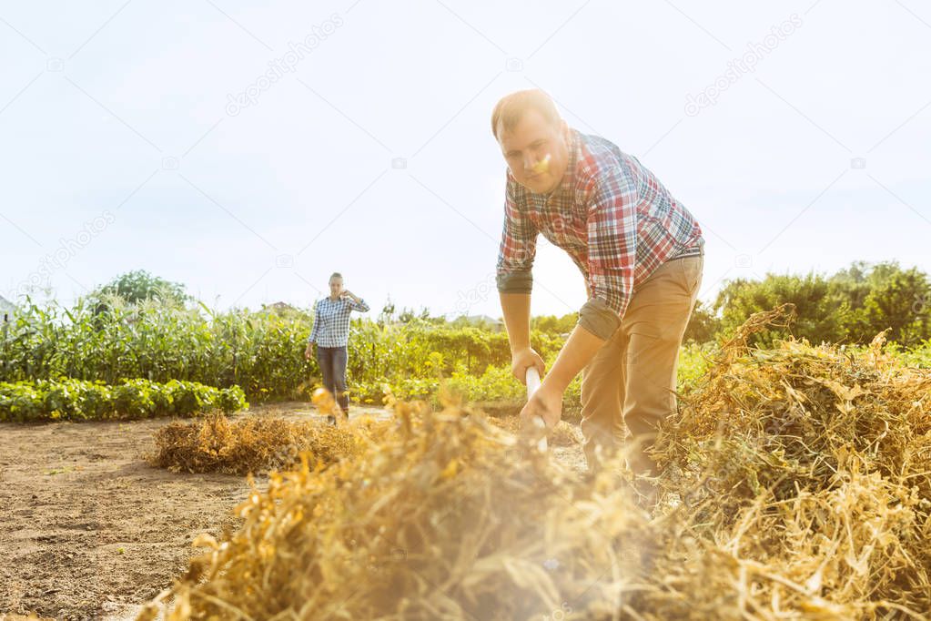 Young and happy farmers couple at their garden in sunny day