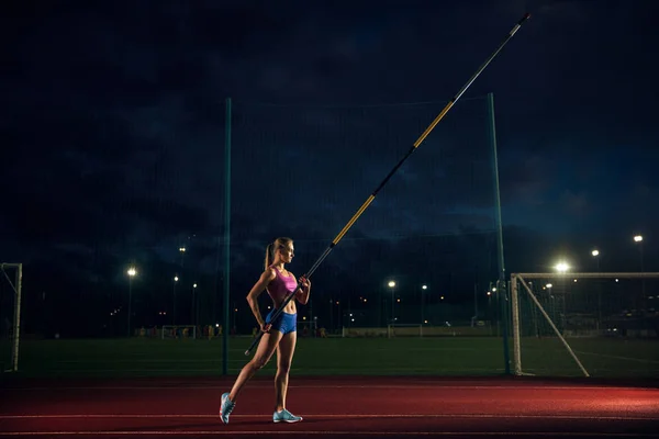 Feminino pole vaulter treinando no estádio à noite — Fotografia de Stock