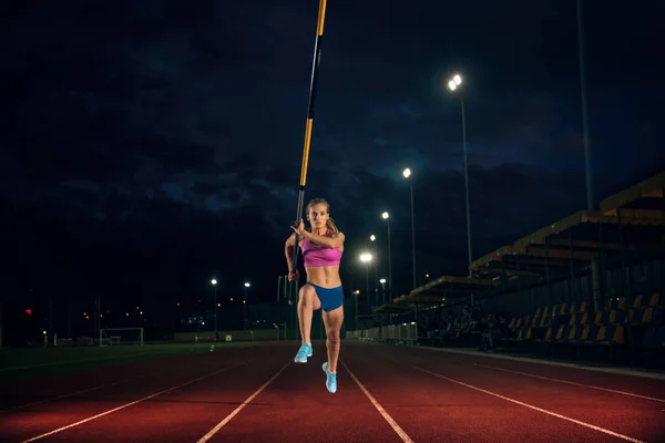 Kvinnlig Pole stavhopparen utbildning på arenan på kvällen — Stockfoto