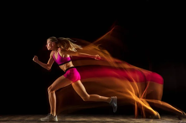 Profesional perempuan relay pelatihan pembalap pada latar belakang studio hitam dalam campuran cahaya — Stok Foto