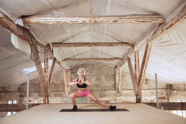 A young athletic woman working out on an abandoned construction site — Stock Photo, Image