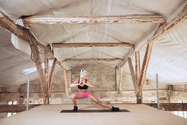 A young athletic woman working out on an abandoned construction site — Stock Photo, Image