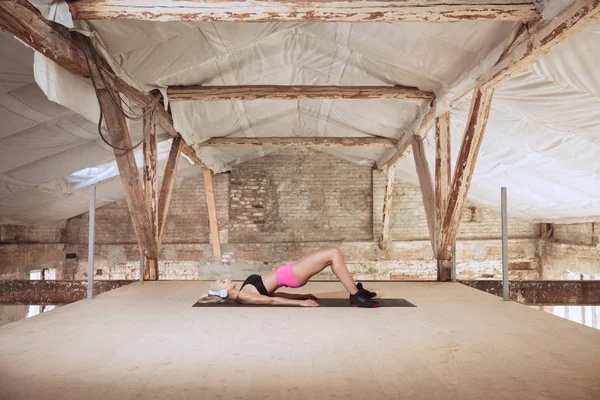 A young athletic woman working out on an abandoned construction site — Stock Photo, Image